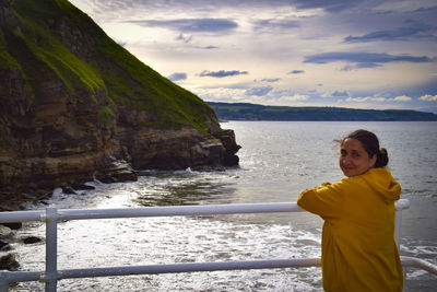 Portrait of woman standing by railing against sea