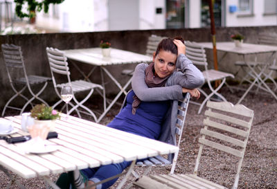 Portrait of young woman sitting on wall