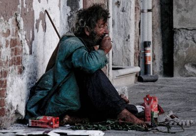 Woman sitting on old wall in city