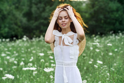 Portrait of young woman standing against plants