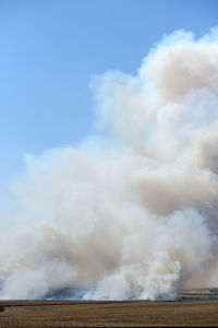 Smoke emitting from volcanic landscape against sky