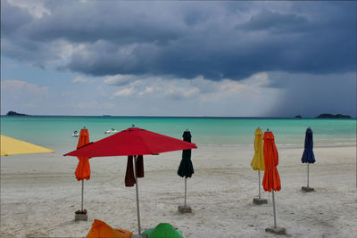 Deck chairs and parasols on beach against sky