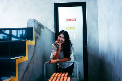Portrait of smiling young woman sitting against wall