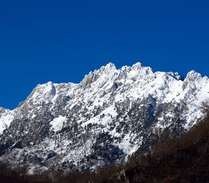 Low angle view of snowcapped mountain against clear blue sky