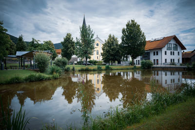 Houses and trees by lake against sky