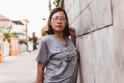 Portrait of woman standing against wall