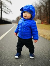 Full length of cute baby boy wearing winter jacket while standing on road