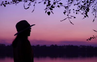 Silhouette of a woman in hat with dreamy purple evening sky in the backdrop
