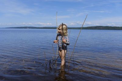 Rear view of woman in lake against sky