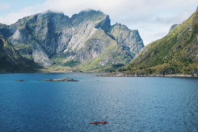 Scenic view of sea by mountain against sky