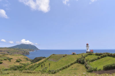 Lighthouse by sea against sky