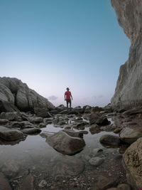 Man standing on rock against sky