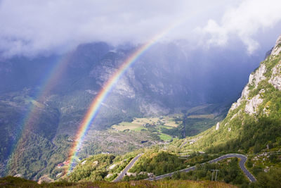 Scenic view of rainbow over mountains against sky