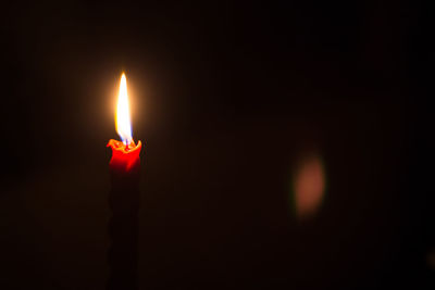 Close-up of lit candle against black background