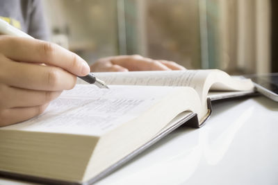 Close-up of hand holding fountain pen while reading book