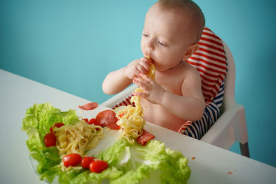 A child eats pasta with lettuce and tomatoes