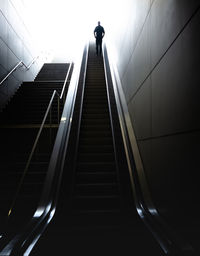 Low angle view of man walking on escalator