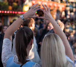 Rear view of women making heart shape with fingers