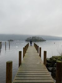 Rear view of wooden pier over sea against sky