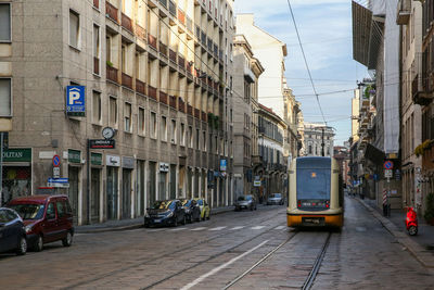 Tram on road along buildings