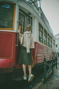 Rear view of woman standing by building in city