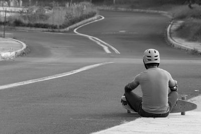 Rear view of man sitting on road