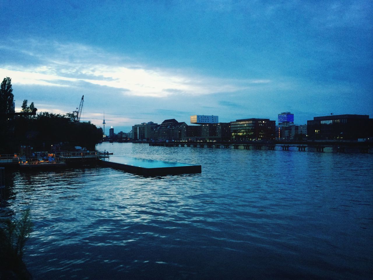 water, sky, building exterior, waterfront, architecture, built structure, nautical vessel, cloud - sky, city, river, transportation, cloud, boat, rippled, mode of transport, blue, sea, reflection, cloudy, cityscape