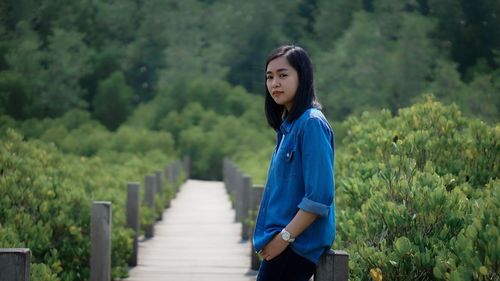 Portrait of young woman standing against trees