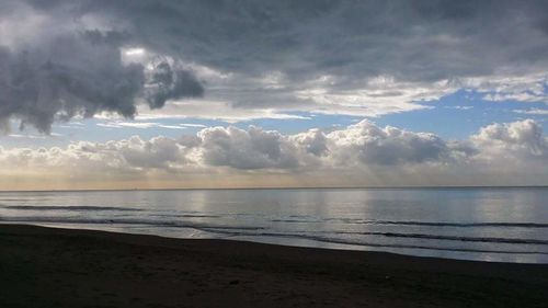 Scenic view of beach against cloudy sky