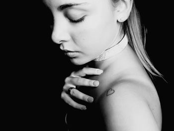 Close-up portrait of young woman against black background