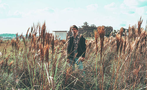 Portrait of woman standing by plants against sky