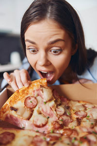 Portrait of young woman holding pizza