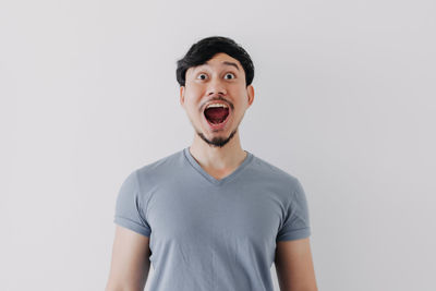 Portrait of young man standing against white background