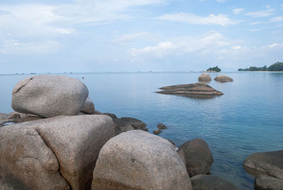 Rocks on beach against cloudy sky