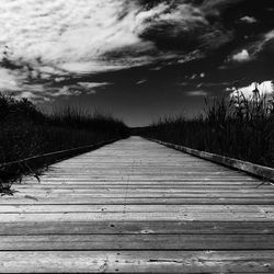 Boardwalk amidst trees against sky