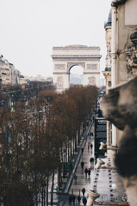 People walking in front of arc de triomphe against sky