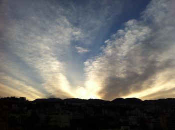 Scenic view of mountains against cloudy sky at sunset