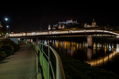 Illuminated bridge over river against sky at night