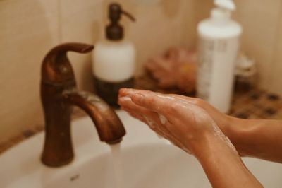 Close-up of woman washing hands in sink at bathroom