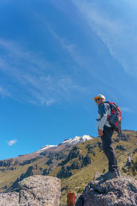Rear view of man standing on mountain against sky