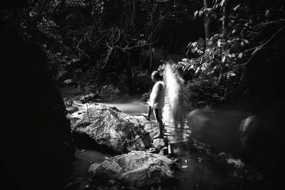 Blurred motion of man standing on rock in forest