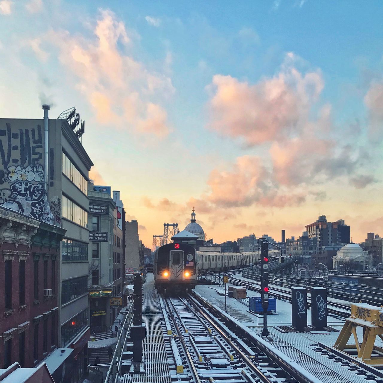 TRAIN ON RAILROAD TRACKS IN CITY AGAINST SKY