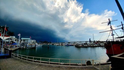 Sailboats moored at harbor against sky in city