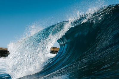 Blue wave splashing on a beach in summer