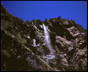 Low angle view of waterfall against clear sky