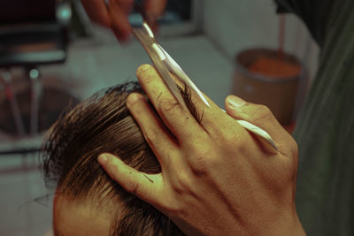 Close-up of barber cutting hair at salon