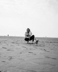 Man with dog sitting on beach