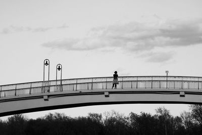 Man walking on bridge against sky