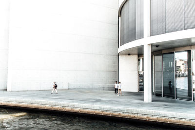 People near modern building by river in city