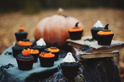 Close-up of cupcakes and pumpkin on table during halloween celebration